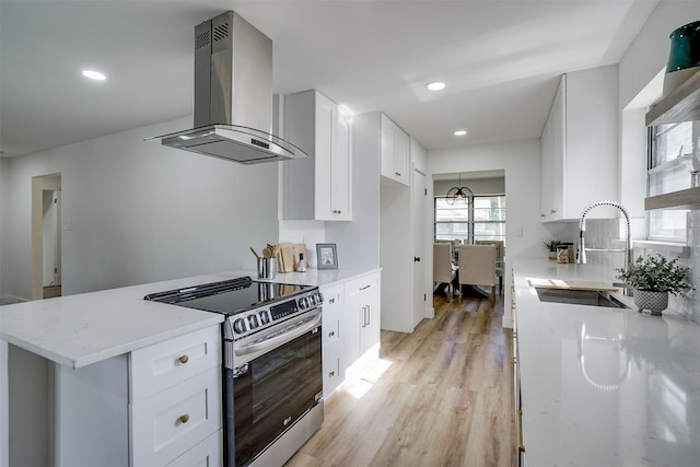 kitchen with wall chimney range hood, sink, electric stove, light hardwood / wood-style floors, and white cabinetry