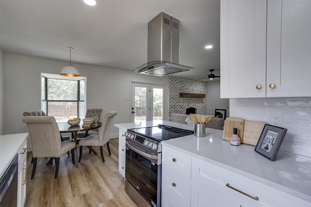 kitchen featuring pendant lighting, white cabinets, wall chimney range hood, decorative backsplash, and stainless steel appliances