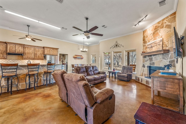 living room featuring crown molding, a fireplace, rail lighting, and ceiling fan with notable chandelier