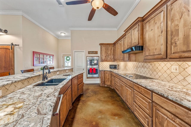 kitchen with a barn door, light stone counters, black electric cooktop, and sink