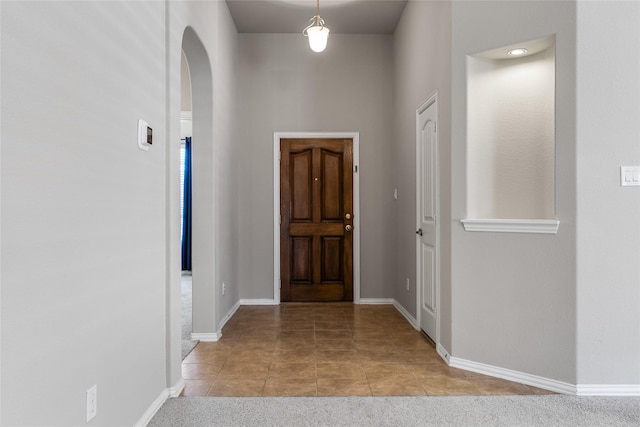 entrance foyer featuring a towering ceiling and light carpet