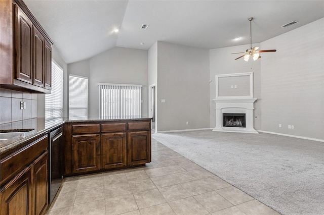 kitchen with dark brown cabinets, stainless steel dishwasher, ceiling fan, light colored carpet, and lofted ceiling