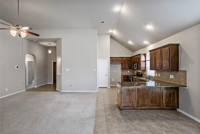 kitchen with stainless steel appliances, dark stone counters, sink, backsplash, and kitchen peninsula