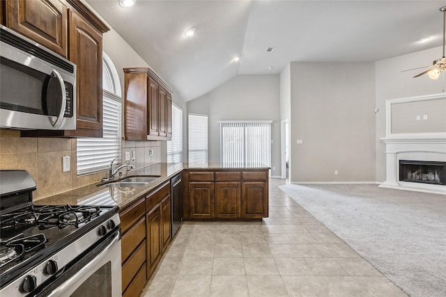 kitchen featuring lofted ceiling, stainless steel appliances, sink, kitchen peninsula, and light colored carpet