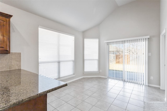 unfurnished dining area featuring light tile patterned floors, plenty of natural light, and vaulted ceiling