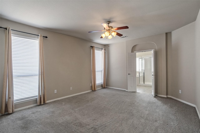 carpeted empty room with ceiling fan and a wealth of natural light