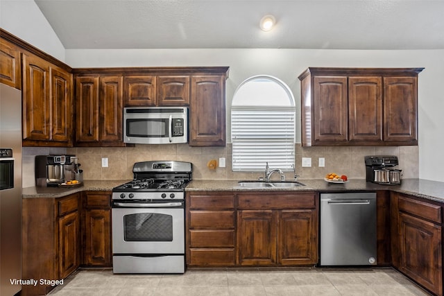 kitchen with decorative backsplash, sink, appliances with stainless steel finishes, and lofted ceiling