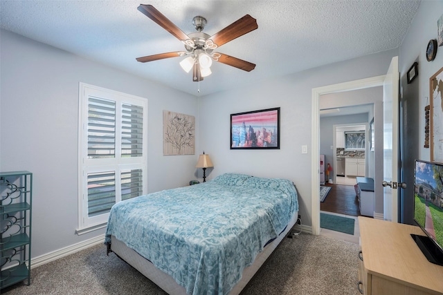 bedroom featuring ceiling fan, dark carpet, and a textured ceiling