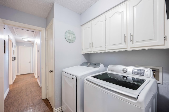 washroom with cabinets, light hardwood / wood-style floors, washing machine and dryer, and a textured ceiling