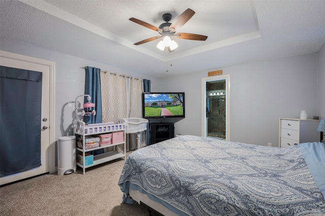 carpeted bedroom featuring a raised ceiling, connected bathroom, a textured ceiling, and ceiling fan