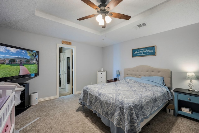 bedroom with a tray ceiling, carpet floors, a textured ceiling, and ceiling fan