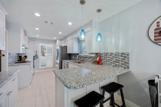 kitchen featuring decorative light fixtures, tasteful backsplash, white cabinets, kitchen peninsula, and stainless steel appliances