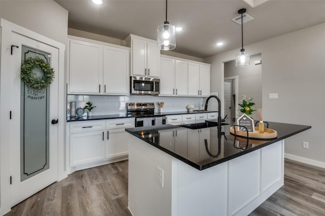 kitchen featuring a center island with sink, white cabinets, and stainless steel appliances