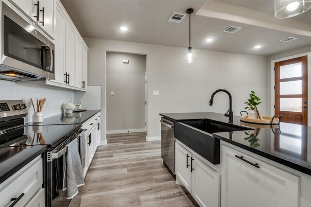 kitchen with backsplash, stainless steel appliances, sink, decorative light fixtures, and white cabinetry