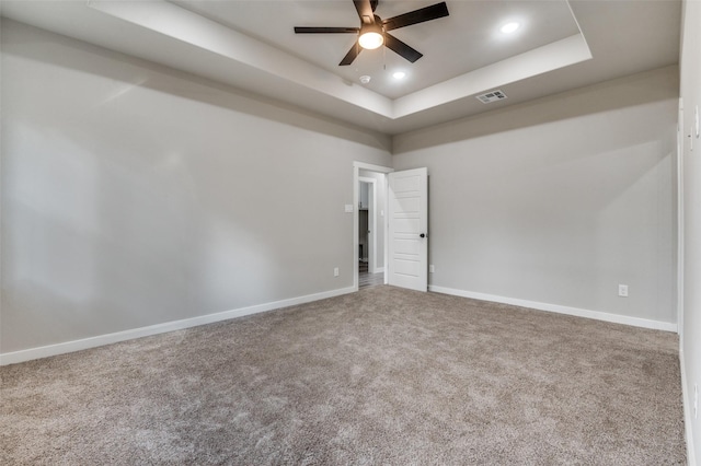 unfurnished room featuring carpet floors, a tray ceiling, and ceiling fan