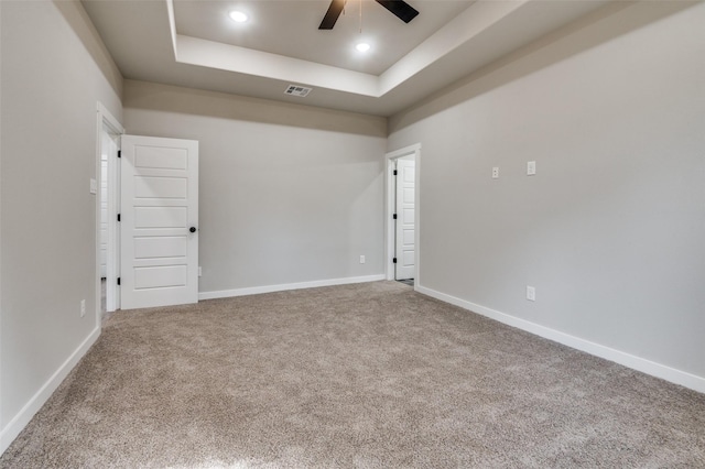 carpeted empty room with a tray ceiling and ceiling fan