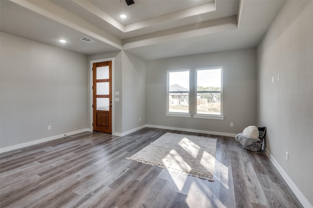 empty room with light hardwood / wood-style floors and a raised ceiling