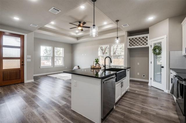 kitchen with stainless steel dishwasher, a raised ceiling, white cabinetry, and sink