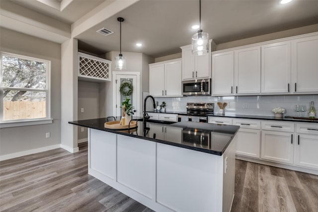 kitchen with white cabinetry, an island with sink, pendant lighting, and appliances with stainless steel finishes