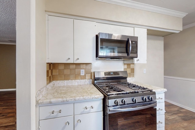 kitchen featuring crown molding, dark hardwood / wood-style flooring, white cabinets, and appliances with stainless steel finishes