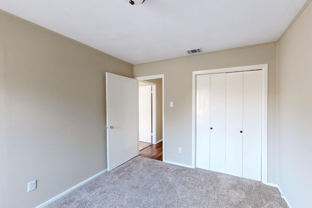 unfurnished bedroom with dark colored carpet and a closet