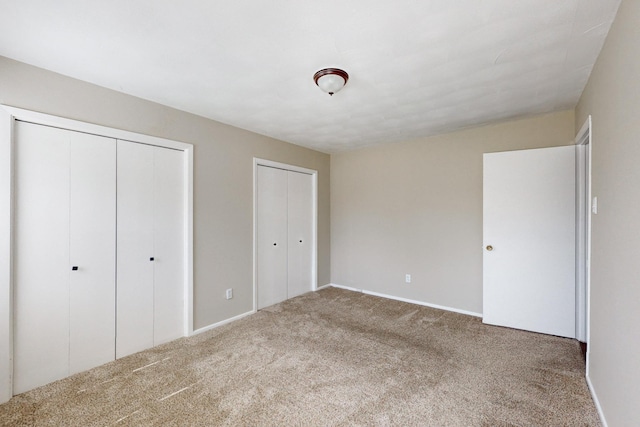 unfurnished bedroom featuring carpet and two closets