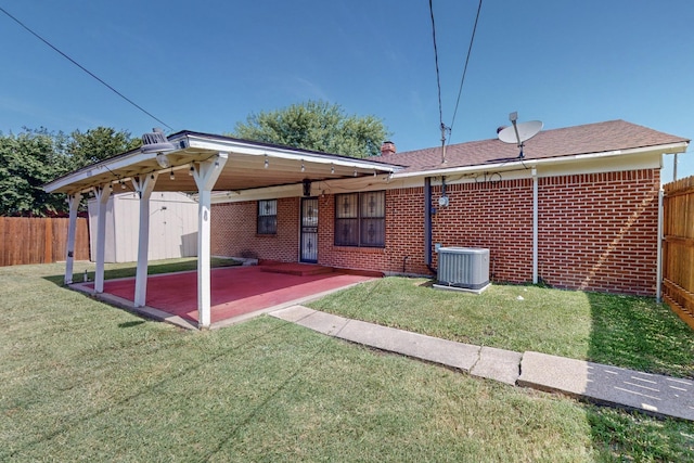 rear view of property featuring a yard, a patio, a storage shed, and central air condition unit