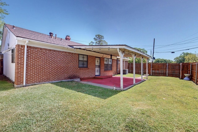 rear view of property featuring a lawn, central AC, and a patio