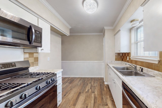 kitchen with ornamental molding, stainless steel appliances, sink, dark hardwood / wood-style floors, and white cabinetry