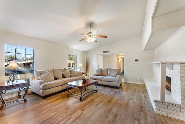 living room featuring a fireplace, hardwood / wood-style floors, vaulted ceiling, and ceiling fan