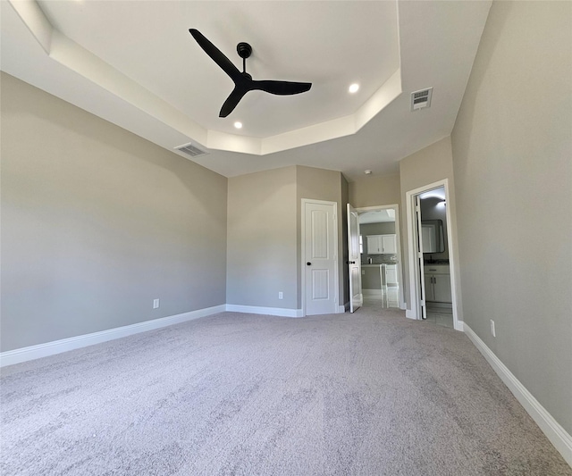 unfurnished bedroom featuring carpet, a tray ceiling, ceiling fan, and ensuite bathroom