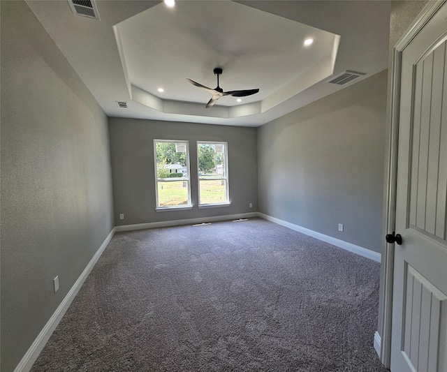 carpeted spare room with ceiling fan and a tray ceiling