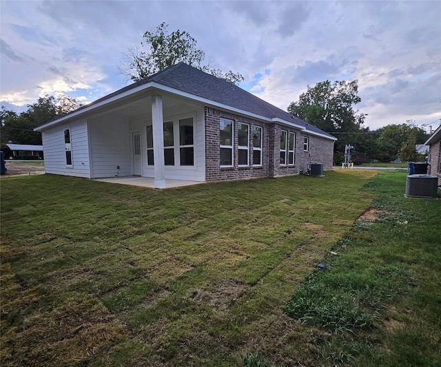 rear view of property with a lawn, cooling unit, and a patio