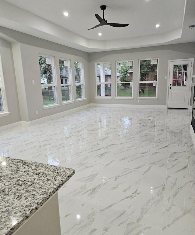 living room featuring a raised ceiling and ceiling fan