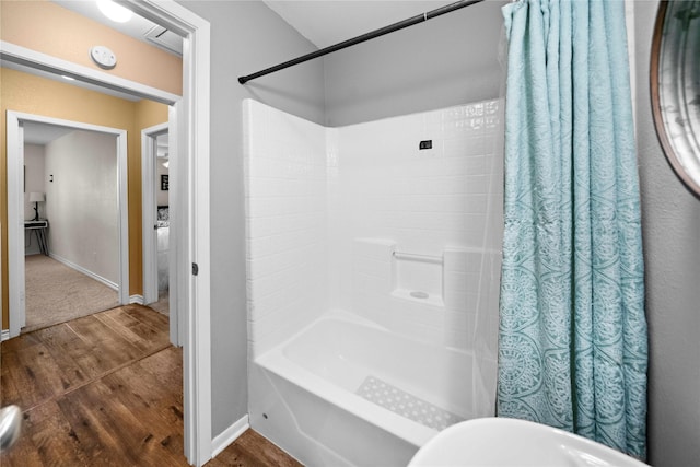 bathroom with hardwood / wood-style flooring and shower / bath combo with shower curtain