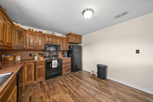 kitchen with dark hardwood / wood-style flooring, black appliances, and sink