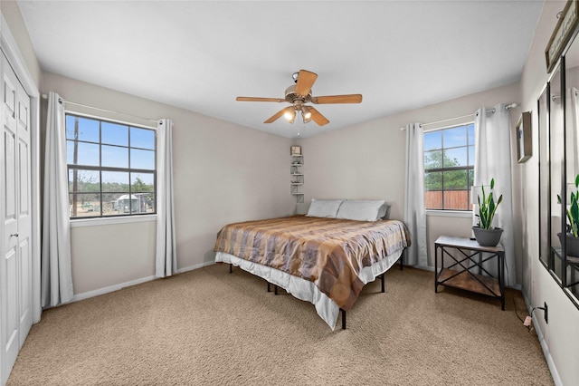 carpeted bedroom featuring ceiling fan, multiple windows, and a closet