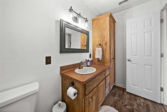 bathroom with hardwood / wood-style floors, vanity, and toilet