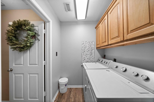 clothes washing area featuring cabinets, dark wood-type flooring, and washing machine and clothes dryer