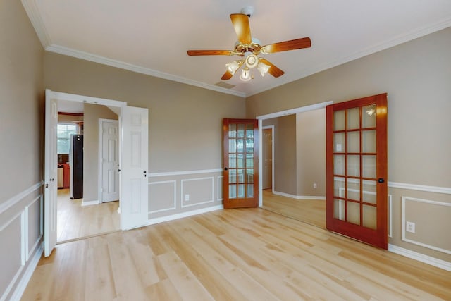 spare room featuring crown molding, ceiling fan, light hardwood / wood-style floors, and a wealth of natural light