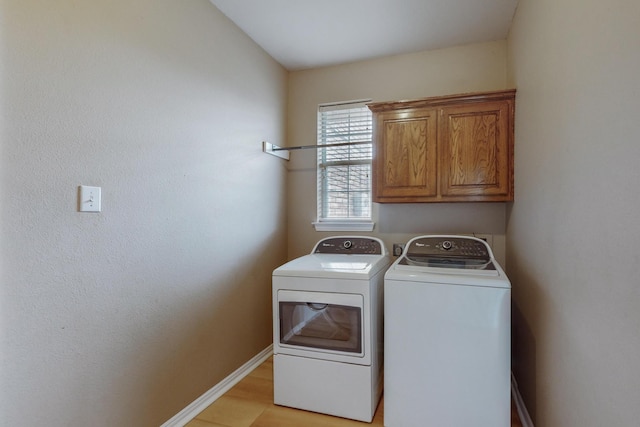 laundry area featuring cabinets, washer and dryer, and light wood-type flooring