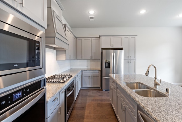 kitchen with light stone counters, sink, dark hardwood / wood-style floors, and appliances with stainless steel finishes