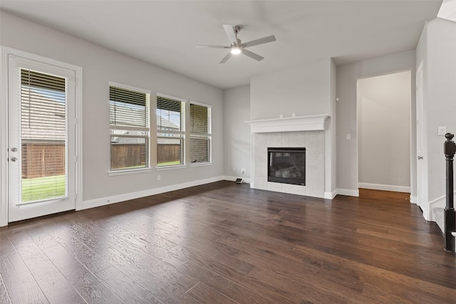 unfurnished living room featuring a fireplace, dark hardwood / wood-style flooring, a wealth of natural light, and ceiling fan