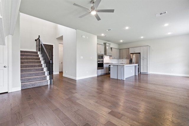 unfurnished living room featuring ceiling fan, sink, and dark hardwood / wood-style floors