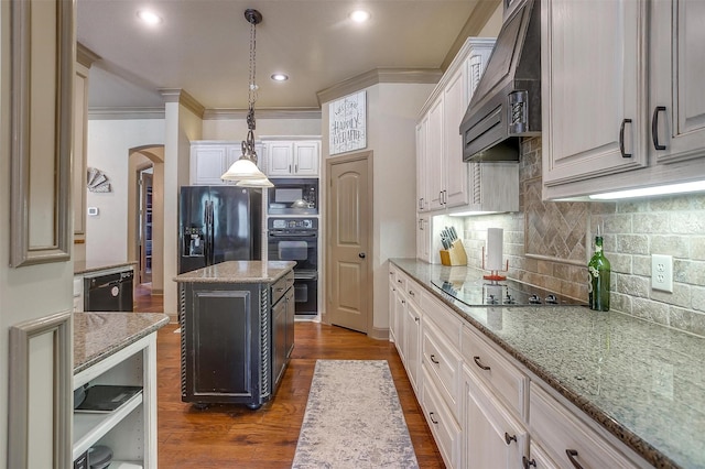 kitchen with light stone counters, custom exhaust hood, black appliances, white cabinetry, and a kitchen island