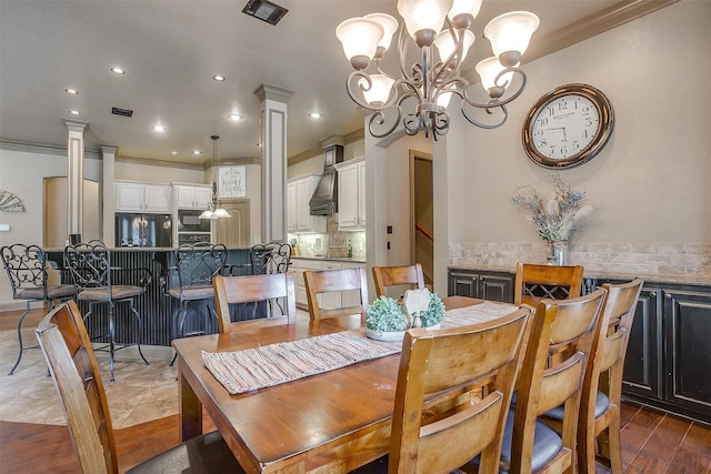 dining space with dark hardwood / wood-style flooring, ornamental molding, ornate columns, and a chandelier