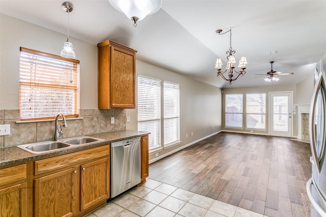 kitchen with tasteful backsplash, ceiling fan with notable chandelier, stainless steel appliances, sink, and light hardwood / wood-style flooring