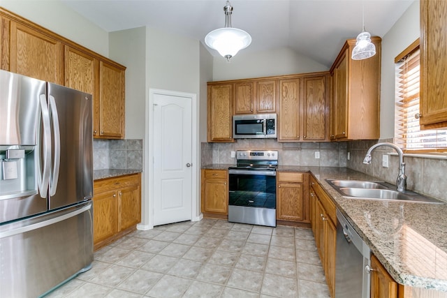 kitchen with sink, tasteful backsplash, vaulted ceiling, decorative light fixtures, and appliances with stainless steel finishes