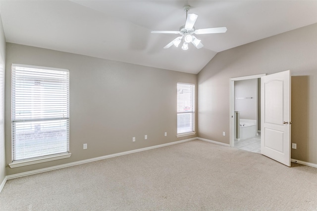 unfurnished bedroom with ceiling fan, light colored carpet, lofted ceiling, and ensuite bath