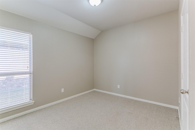 carpeted spare room featuring vaulted ceiling